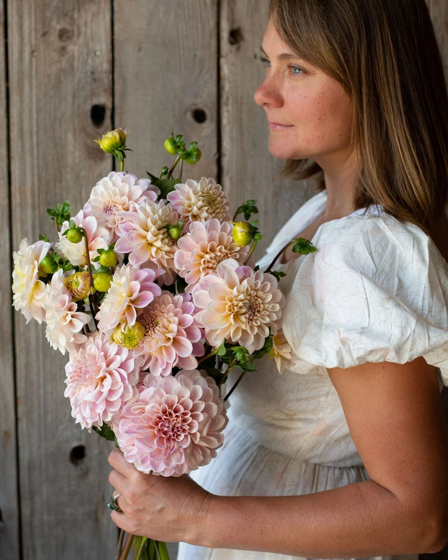 Woman holding a bouquet of flowers against a wooden background
