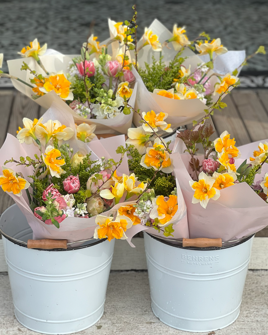 Bouquets of flowers in white buckets on a wooden surface