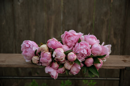 Bouquet of pink peonies on a wooden surface with a wooden background