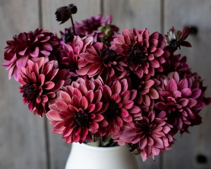 Bouquet of pink and purple flowers in a white vase against a wooden background