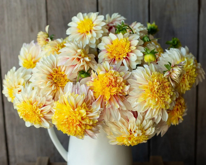 Bouquet of yellow and white flowers in a white vase against a wooden background