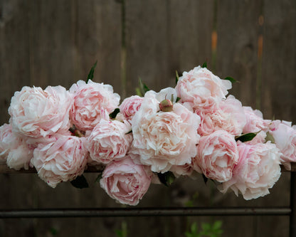 Bouquet of pink peonies on a wooden surface with a blurred wooden background