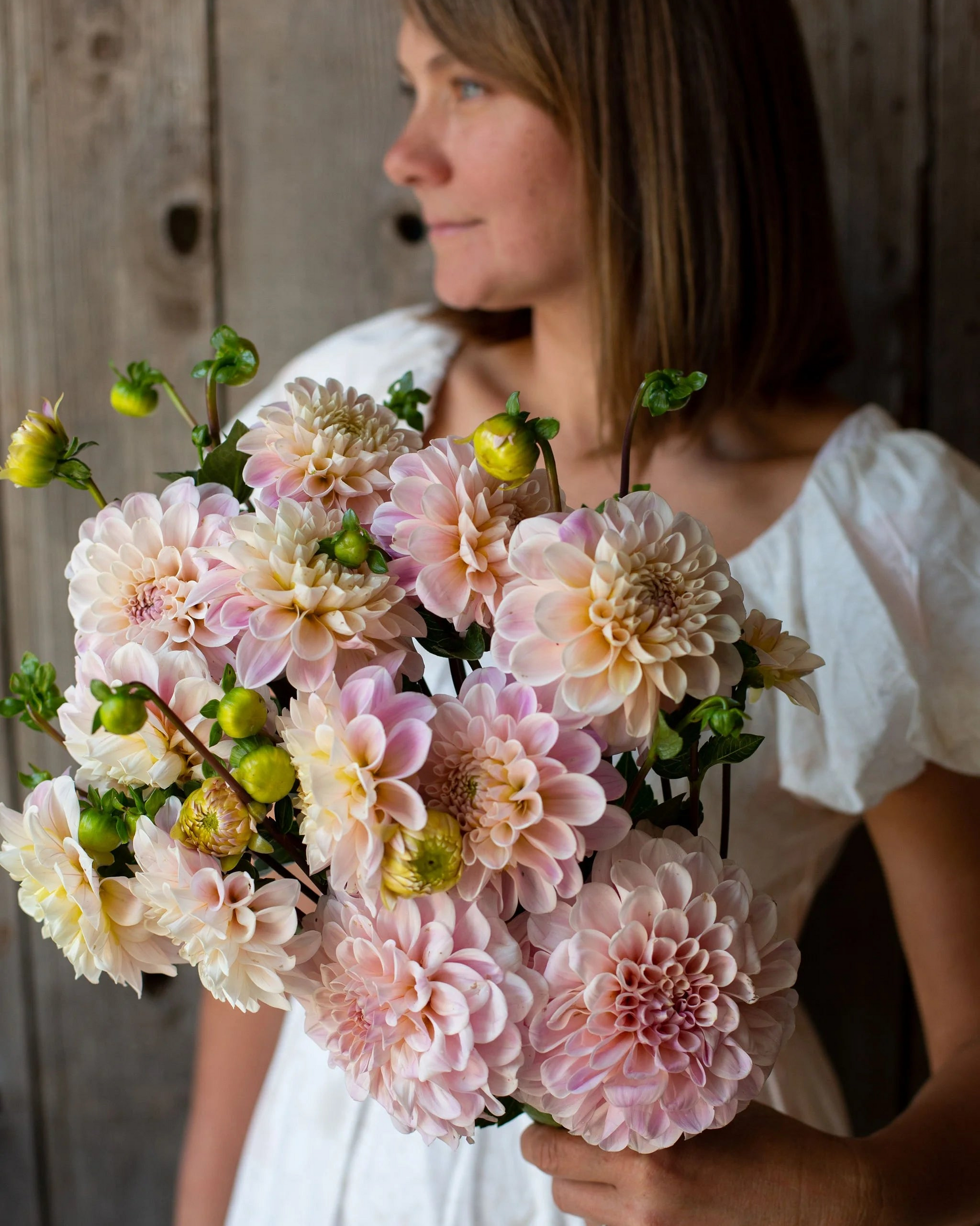 Woman holding a bouquet of pink and white flowers against a wooden background